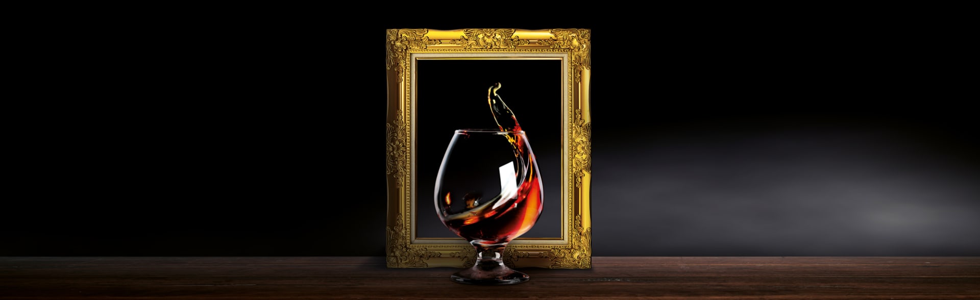 “Image of framed glass of spirit against a dark background”